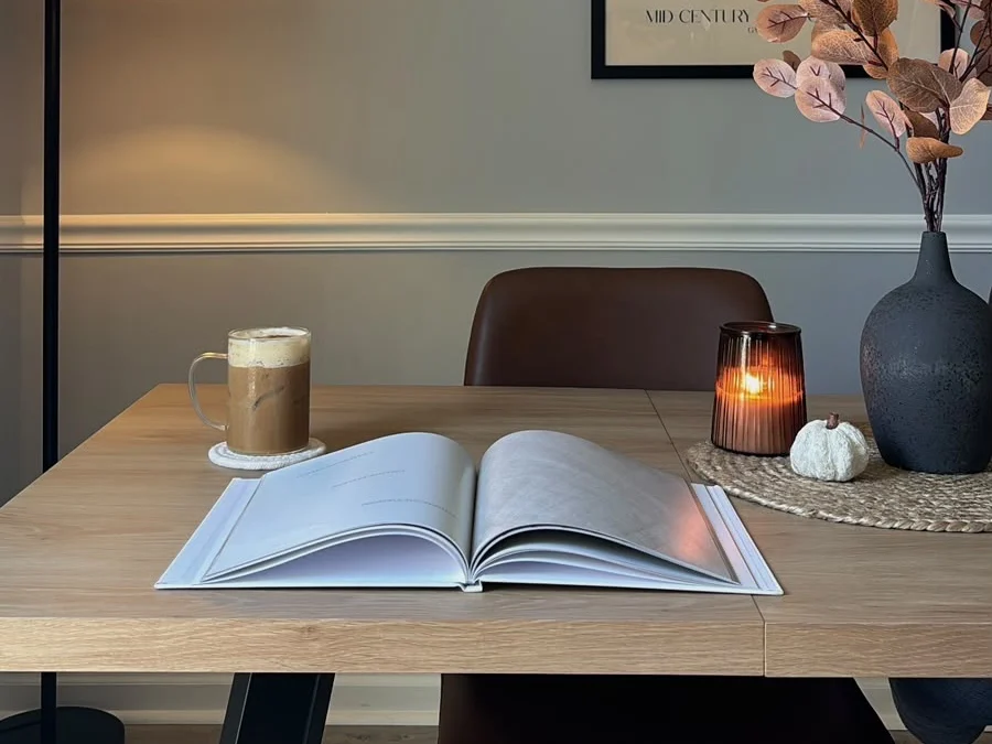 Mesa de madeira com livro aberto, café e vela acesa